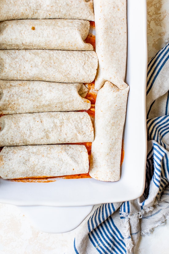 Easy vegetarian enchiladas made with butternut squash and black beans, smothered with enchilada sauce and cheese, then baked in the oven. A delicious recipe that's perfect for meatless Mondays!