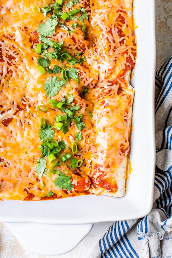 Easy vegetarian enchiladas made with butternut squash and black beans, smothered with enchilada sauce and cheese, then baked in the oven. A delicious recipe that's perfect for meatless Mondays!