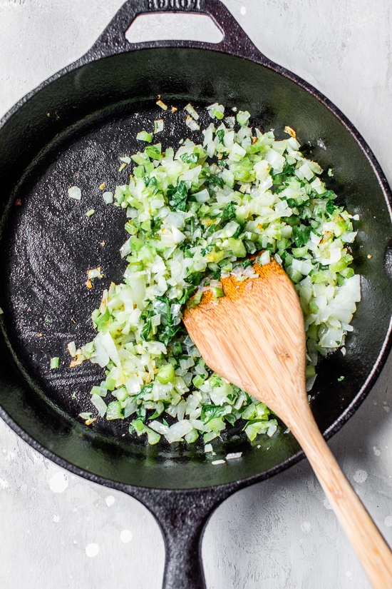 Onions cooking with herbs in a black skillet