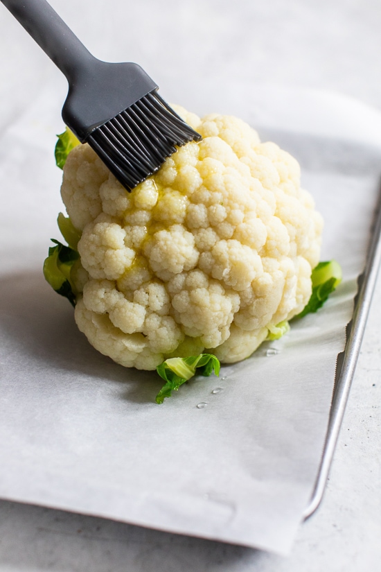 Brushing cauliflower with olive oil.