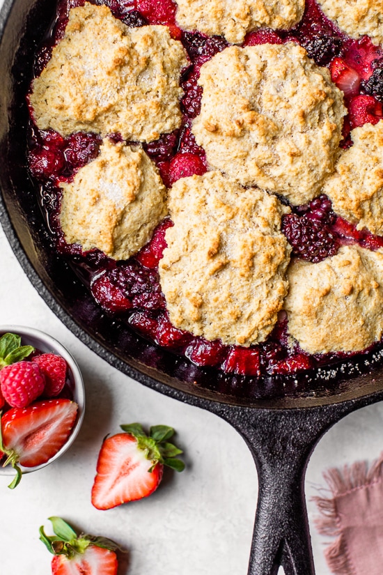 Skillet Mixed Berry Buttermilk Cobbler is made with blackberries, raspberries, and strawberries covered with a delicious biscuit topping and baked in a cast iron skillet.