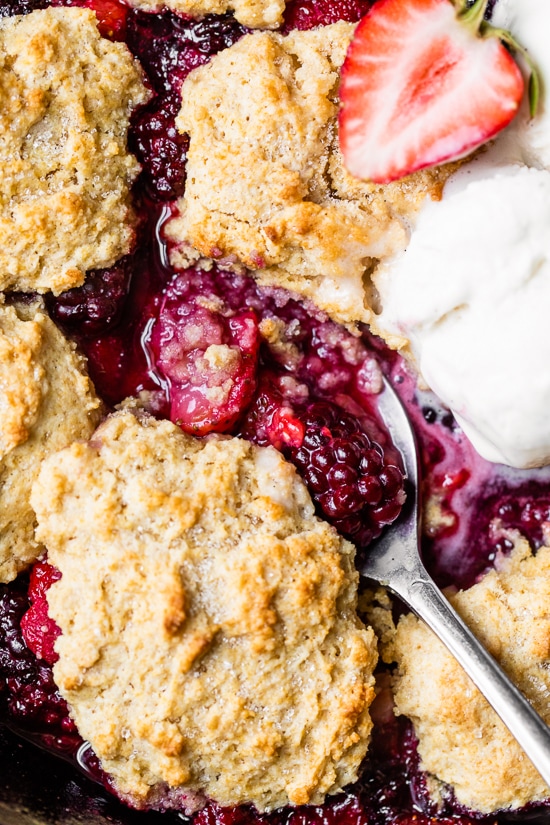 Skillet Mixed Berry Buttermilk Cobbler is made with blackberries, raspberries, and strawberries covered with a delicious biscuit topping and baked in a cast iron skillet.