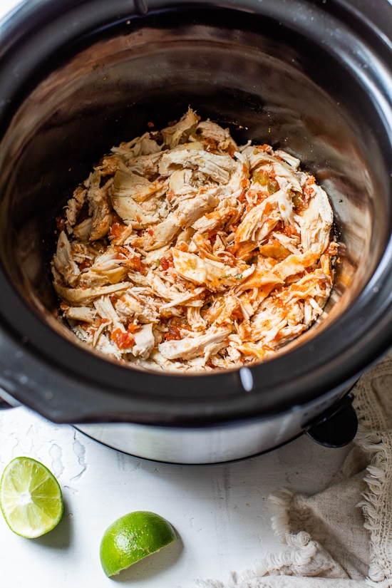 These easy Slow Cooker Chicken Tacos made in the crock pot with chicken breast, salsa, and spices are on repeat in my house!