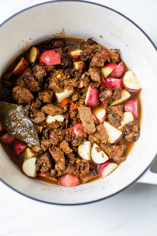 Carne Guisada or Latin Beef Stew is made with chunks of beef simmered in beer with scallions, garlic, tomatoes, cumin and cilantro.